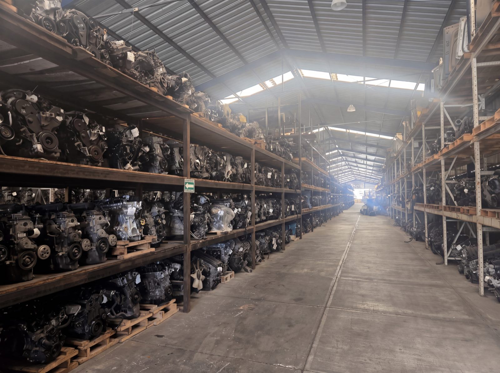 Pasillo de la bodega de El Retorno lleno de motores y transmisiones en estantes